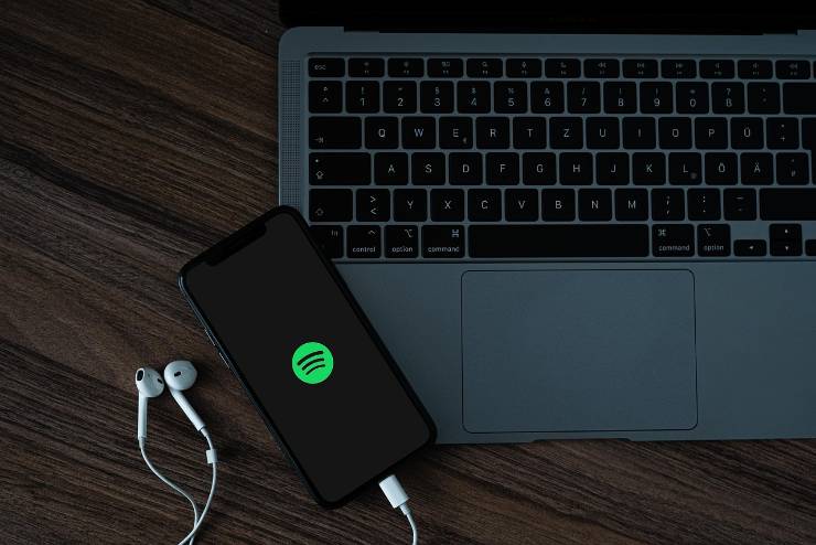 icona di spotify su un telefono con vicino un computer